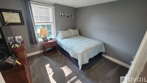 A bedroom with a bed, nightstand, and a framed certificate on the wall.