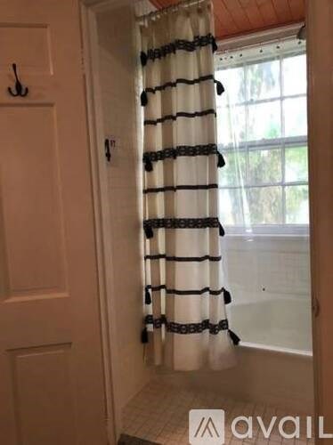 A white door with a black handle is next to a window with a white curtain.