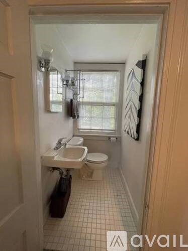 A bathroom with a toilet, sink, and a window.