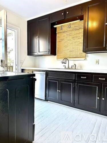 A kitchen with black cabinets and a black refrigerator.