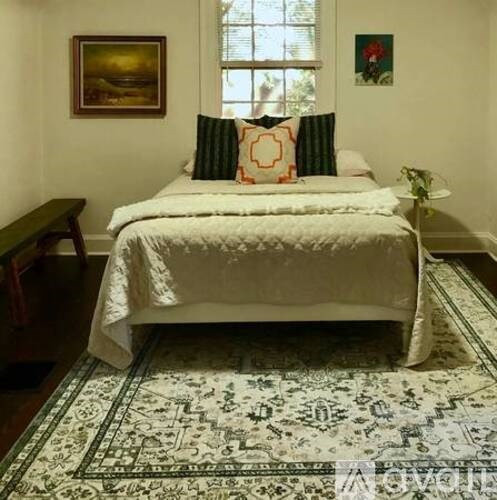 A bedroom with a large bed and a rug on the floor.