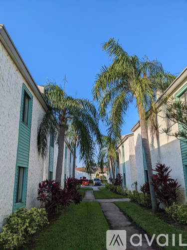 A white building with green shutters and a palm tree in front.