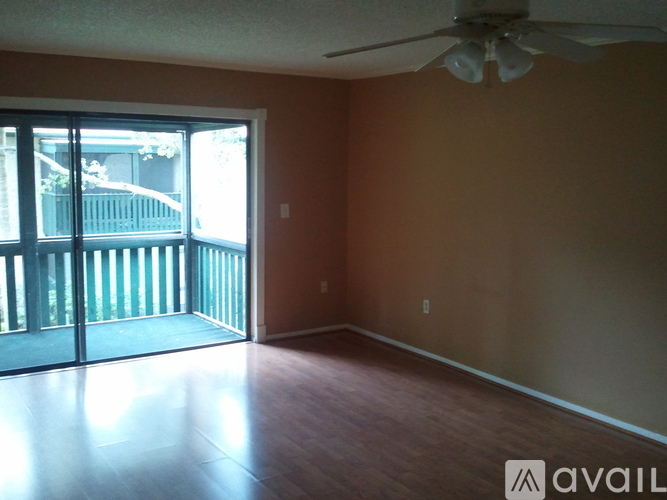 A room with a ceiling fan and sliding glass doors leading to a balcony.