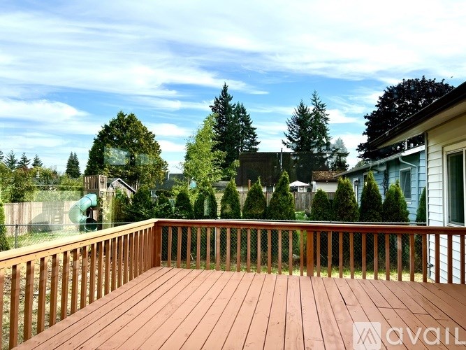 A wooden deck with a railing and trees in the background.