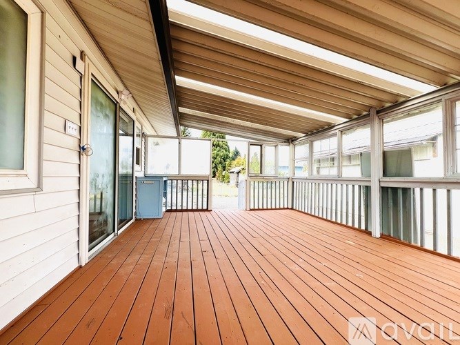 A wooden deck with a white wall and sliding glass doors.