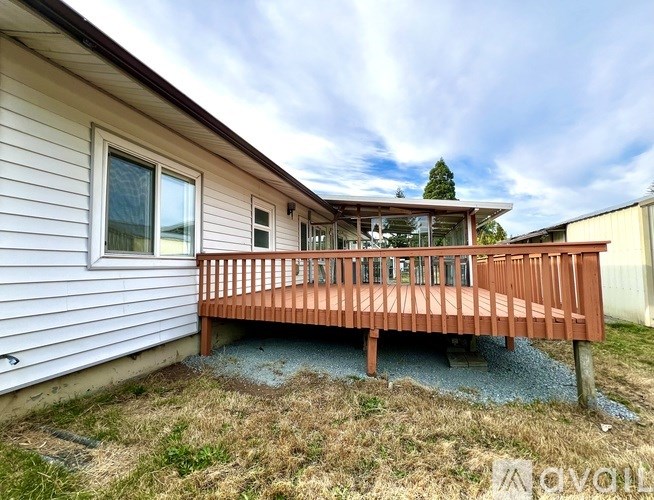 A house with a deck and a tree in the background.