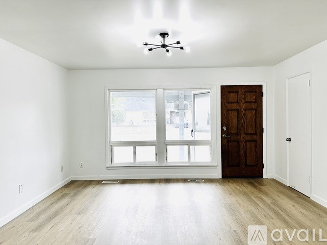 A room with a ceiling fan and a large window with a view of a street.