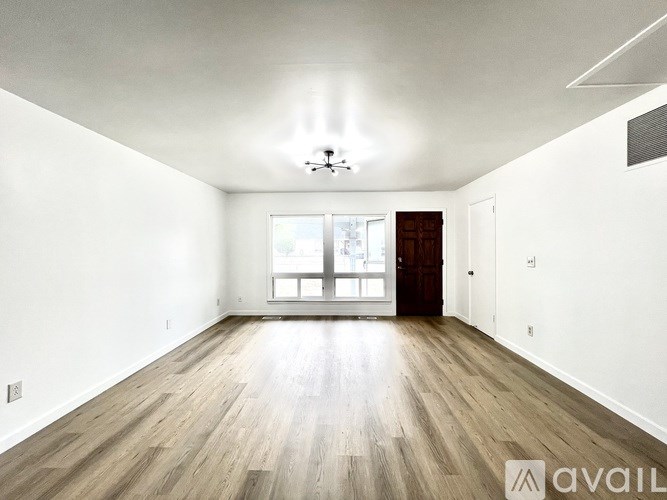 A spacious room with wooden floors and a large window.