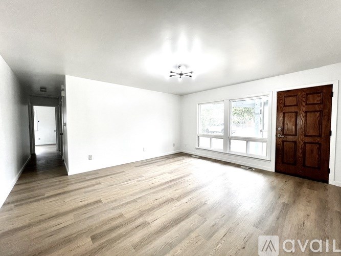 A spacious room with wooden flooring and a large window.