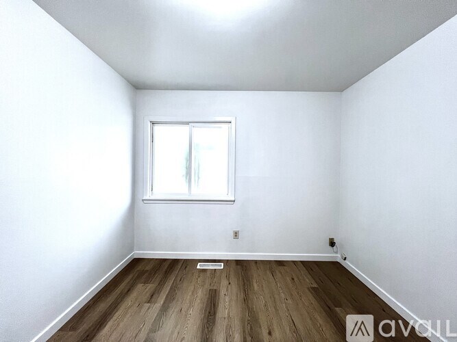 A room with a window and wooden flooring.