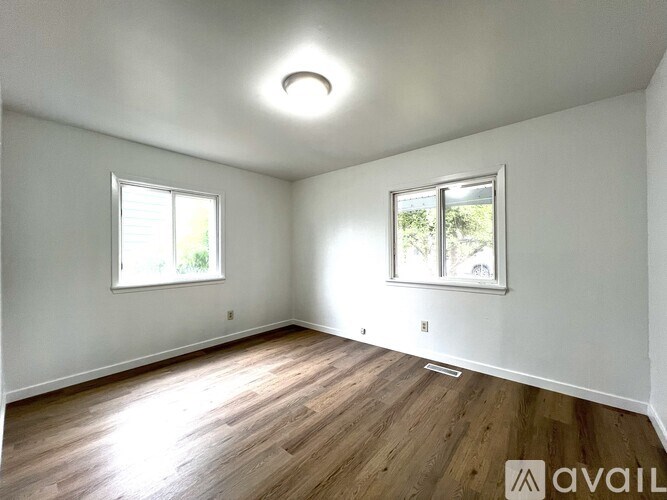 A room with wooden floors and two windows.