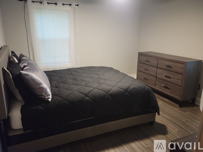 A bedroom with a bed, nightstand, and dresser.