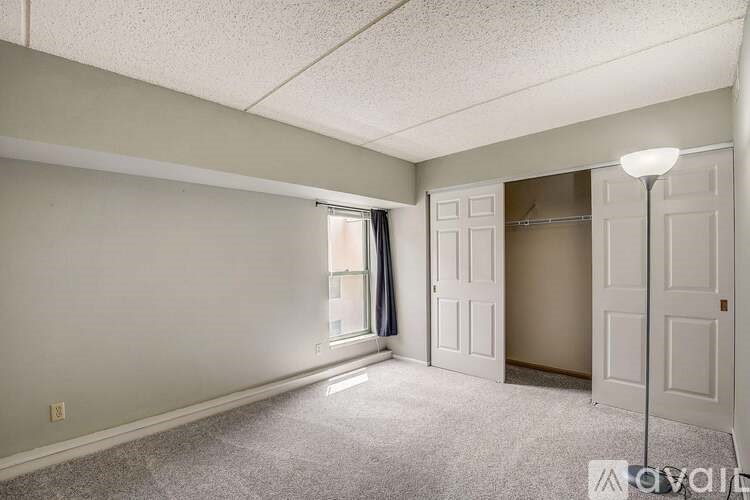 A room with a carpeted floor and a window with curtains.