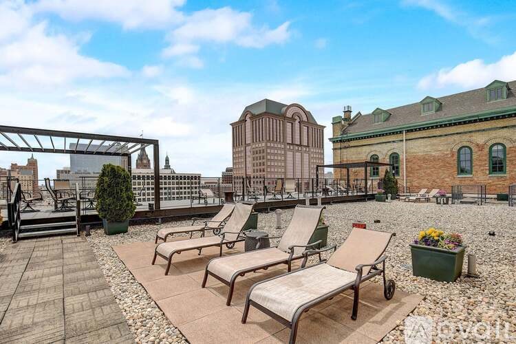 A patio with chairs and a table is surrounded by buildings.