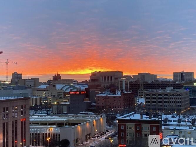 A cityscape at sunset with buildings and a crane visible.