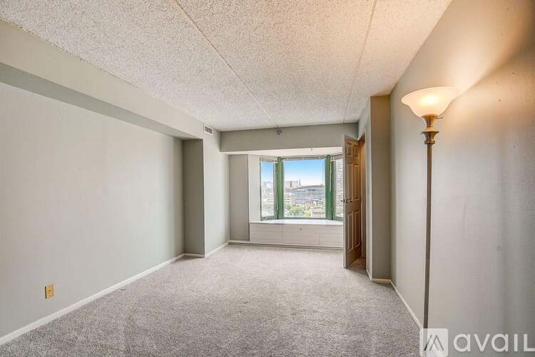 A room with a carpeted floor and a window overlooking a building.