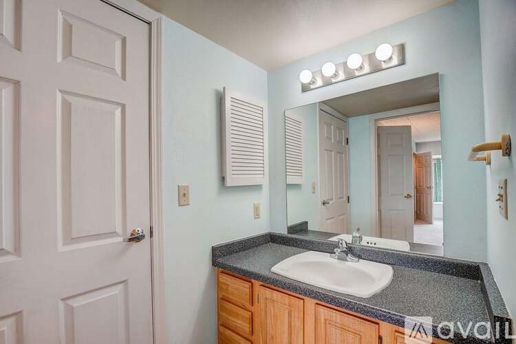 A bathroom with a sink, mirror, and lighting fixture.