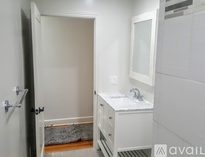 A bathroom with a sink, mirror, and a rug on the floor.