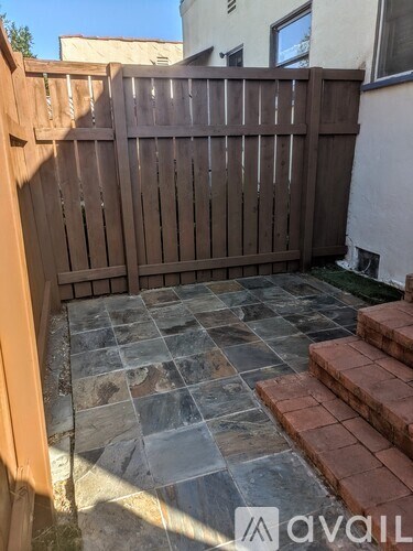 A wooden fence and steps lead to a patio with a stone floor.