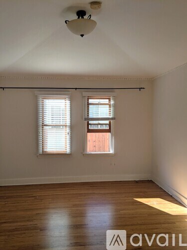 A room with wooden floors and a window with blinds.