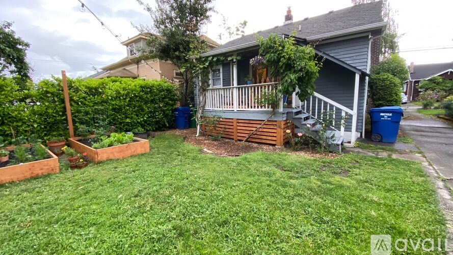 A house with a blue trash can in front of it.