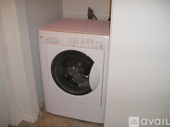 A white washing machine with a pink top is in a room.
