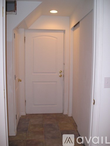 A white door is in a hallway with a tiled floor.