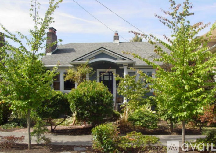 A house with a grey roof and a small porch surrounded by trees.