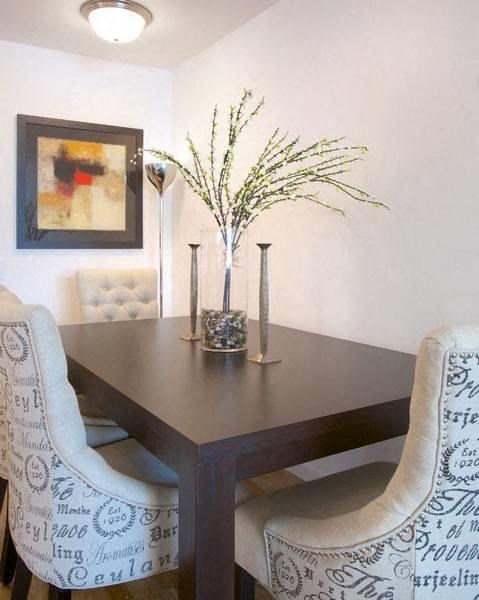 a dining room table with two chairs and a vase of flowers