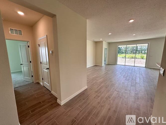 A room with wooden flooring and a large window overlooking a field.