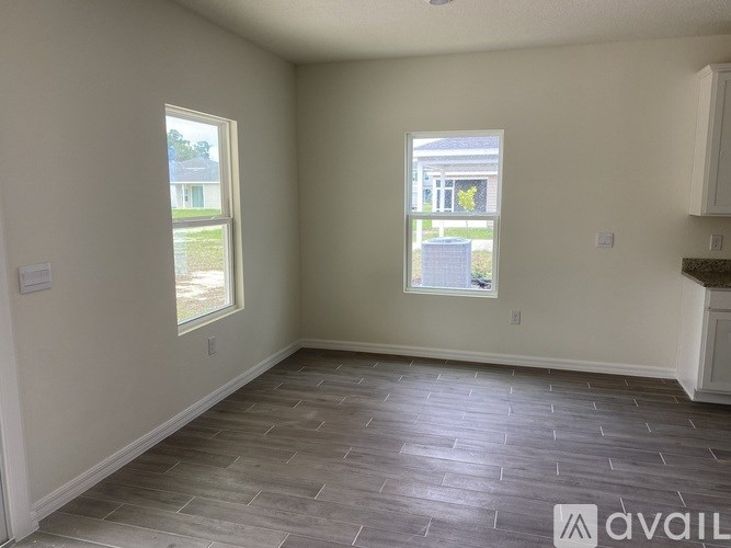 A room with tiled flooring and two windows.
