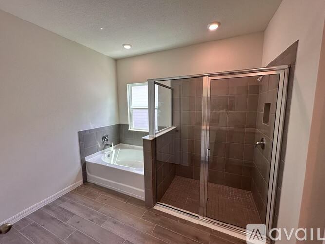 A bathroom with a glass shower door and a bathtub.