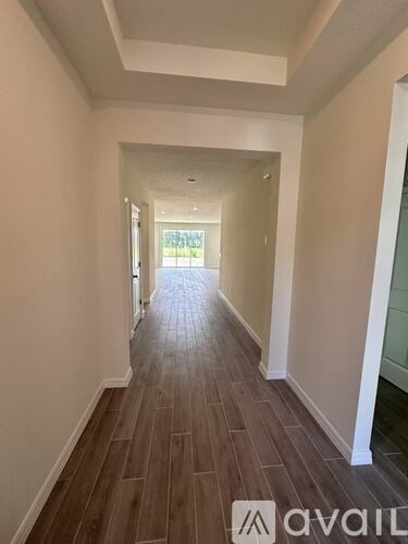 A long hallway with wood flooring and white walls.