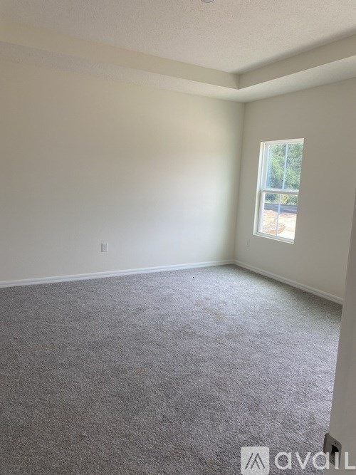 A room with a carpeted floor and a window.