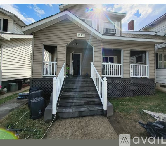 A house with a front porch and a black trash can.