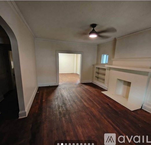 A room with a ceiling fan and wooden floors.