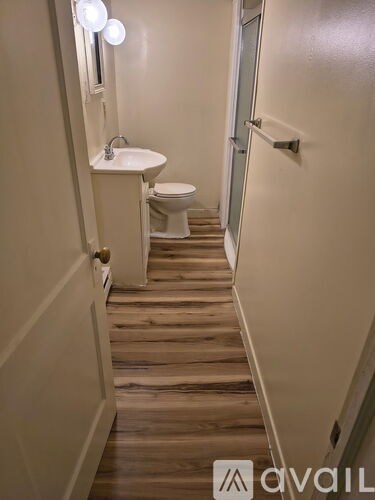 A bathroom with a toilet, sink, and wooden stairs.