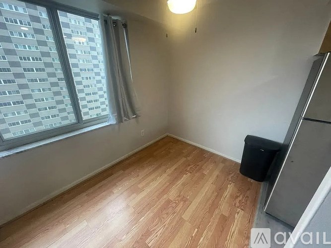 A room with wooden flooring and a window with a view of a building outside.