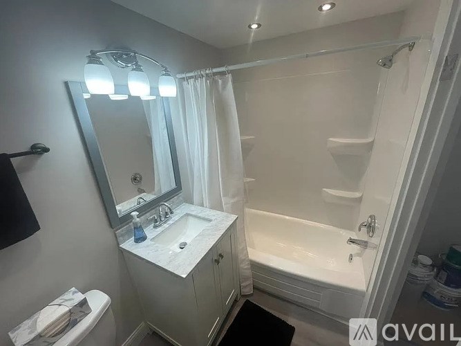 A bathroom with a white sink, mirror, and bathtub.