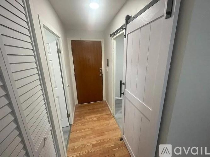 A hallway with a wooden floor and white walls.