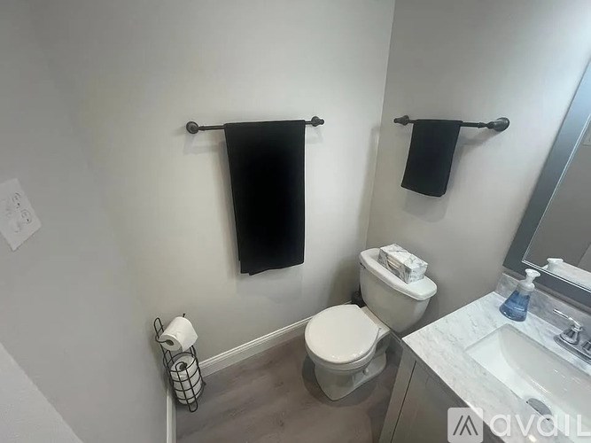 A bathroom with a toilet, sink, and towel racks.