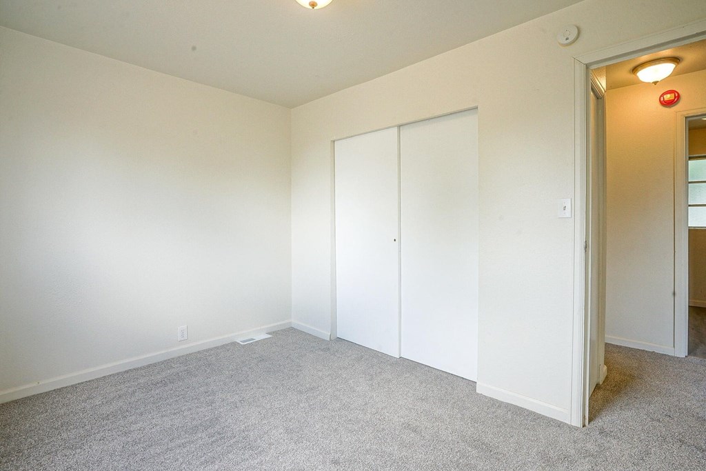 A room with white walls and carpeted floor with a white door.