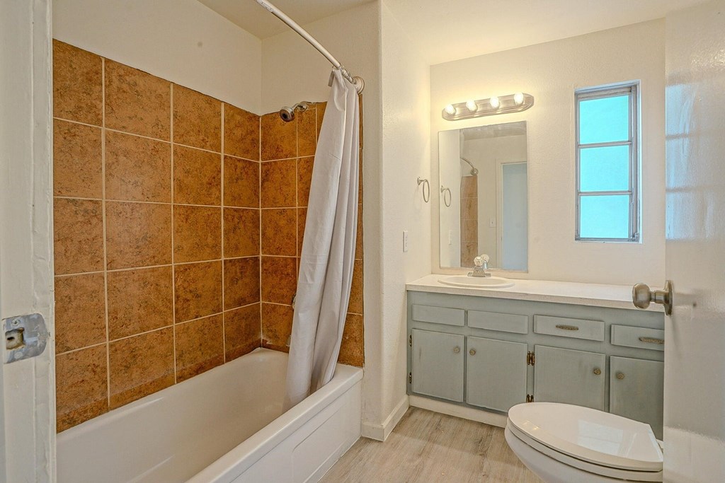 A bathroom with brown tiles and a white bathtub.