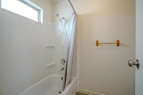 A white bathroom with a tub and a towel rack.