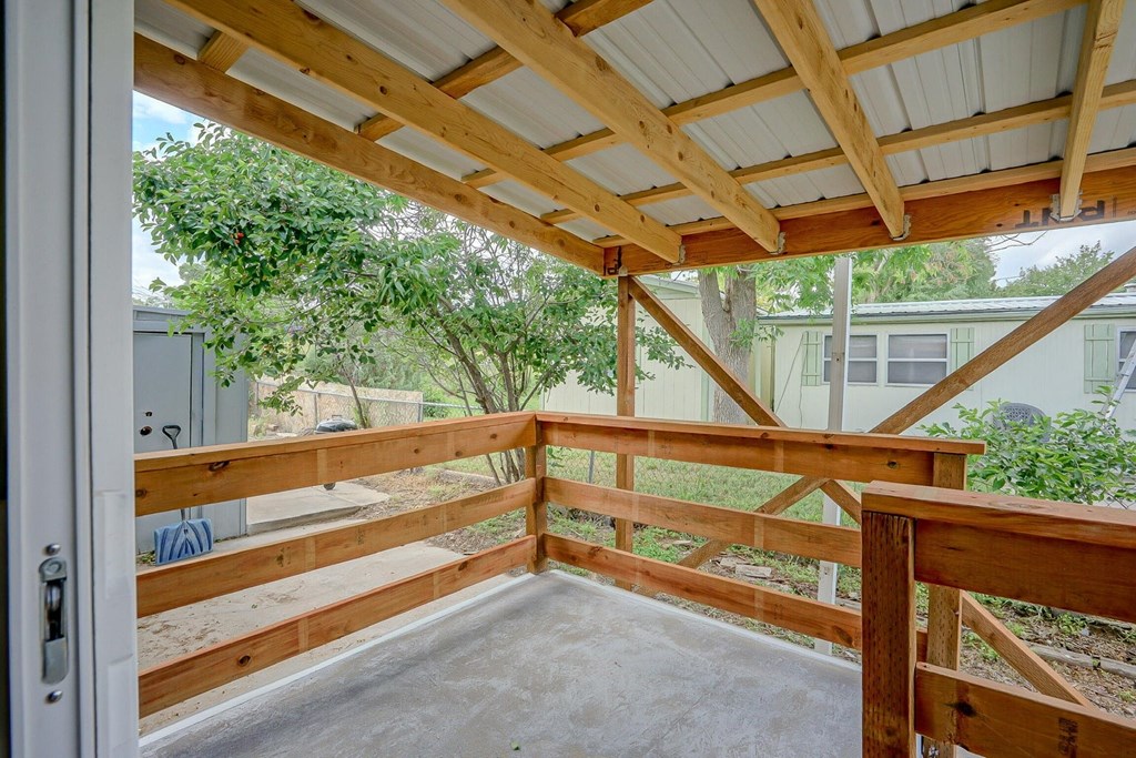 A wooden deck with a roof and a door.