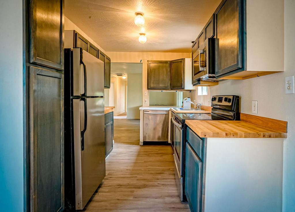 A kitchen with a refrigerator, microwave, and oven.