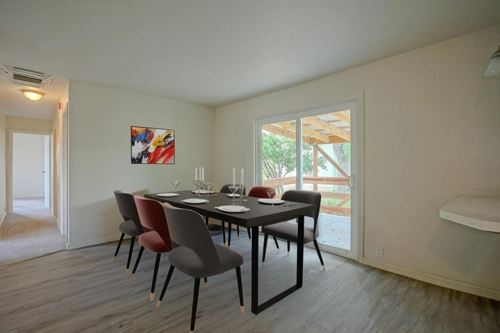 A dining room with a table set for two and a painting on the wall.