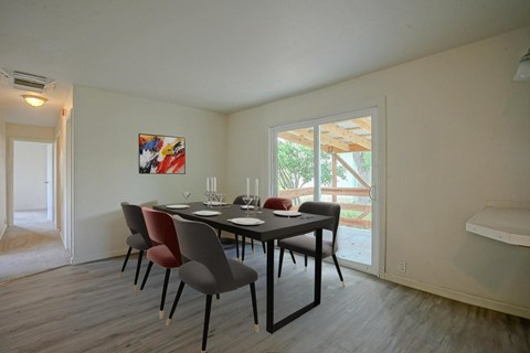 A dining room with a table set for two and a painting on the wall.