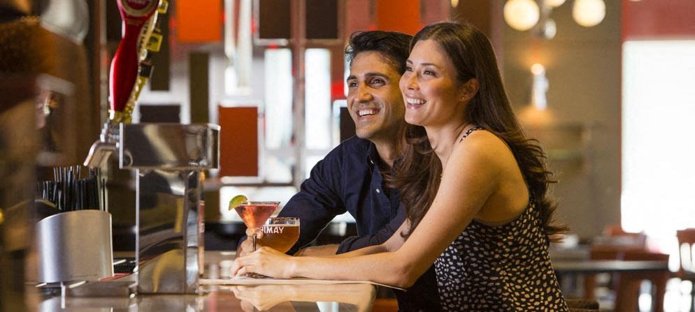 a man and woman sitting at a bar with a drink