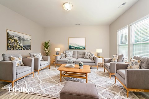 A living room with a grey couch, a wooden coffee table, and a painting on the wall.